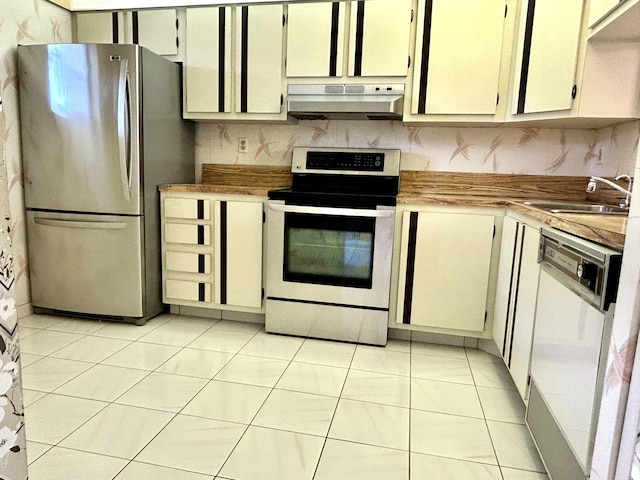 kitchen with dishwasher, sink, stainless steel fridge, stove, and light tile patterned flooring