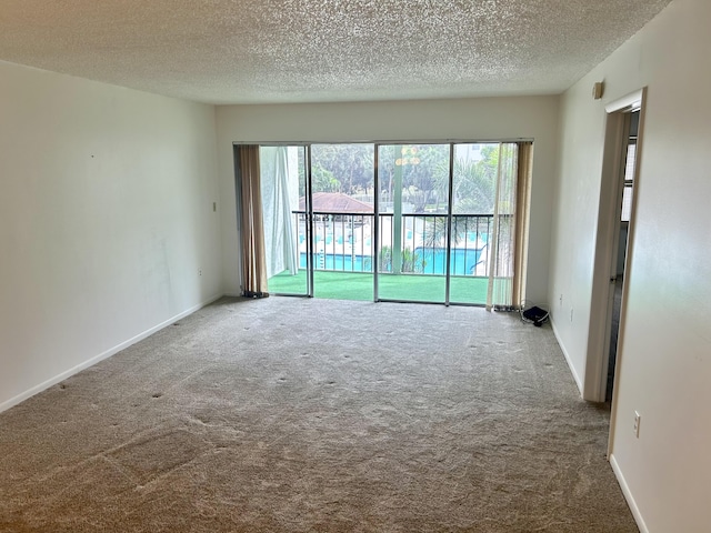 empty room featuring carpet, baseboards, and a textured ceiling