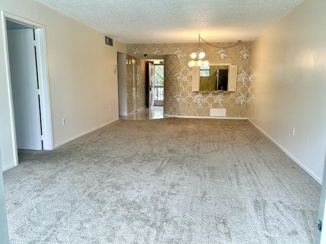 unfurnished living room with wallpapered walls, carpet, visible vents, and a textured ceiling