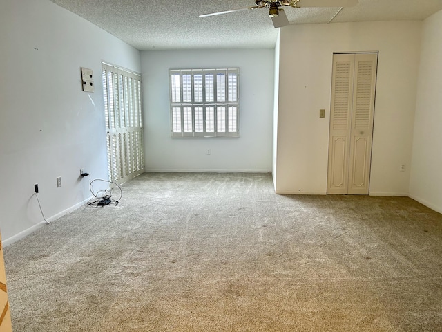 spare room featuring ceiling fan, light colored carpet, and a textured ceiling