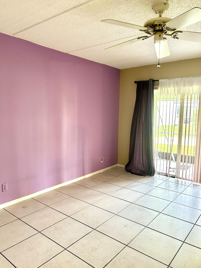 empty room with tile patterned flooring, ceiling fan, and a textured ceiling