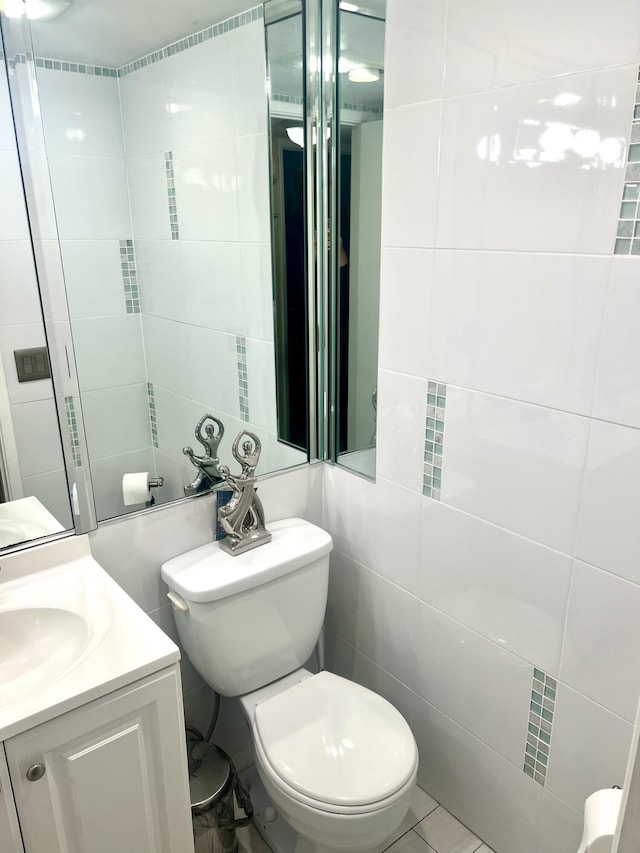 bathroom with tile patterned floors, vanity, tile walls, and toilet