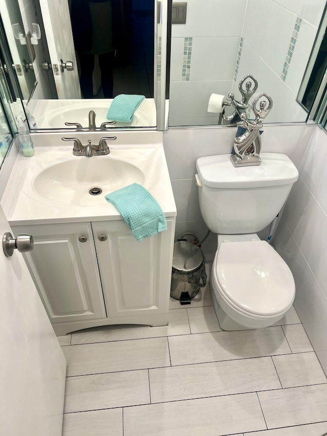 bathroom with vanity, tile walls, and toilet