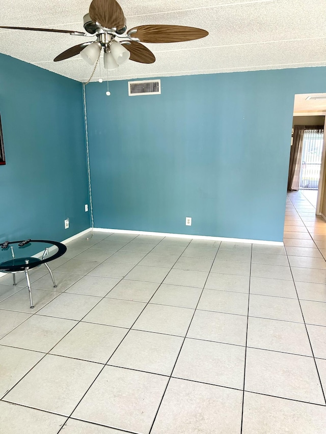 spare room featuring light tile patterned floors, a textured ceiling, and ceiling fan