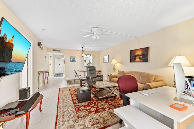 living room featuring ceiling fan, light tile patterned flooring, and a textured ceiling