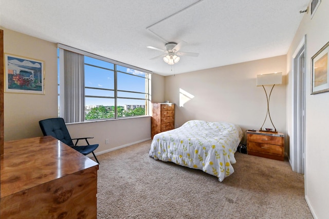 bedroom with ceiling fan, light colored carpet, and a textured ceiling