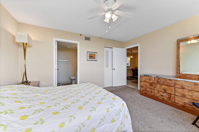 bedroom featuring ceiling fan, carpet floors, ensuite bathroom, and a textured ceiling