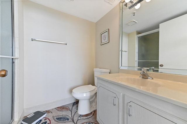 bathroom featuring tile patterned floors, vanity, toilet, and a shower with shower door