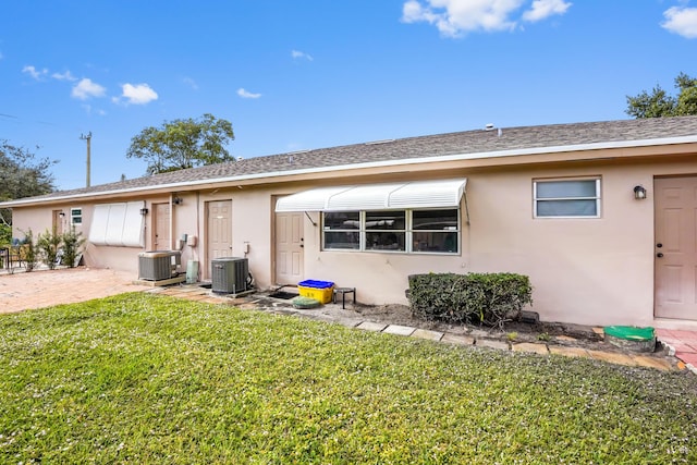 rear view of property featuring a lawn and central AC