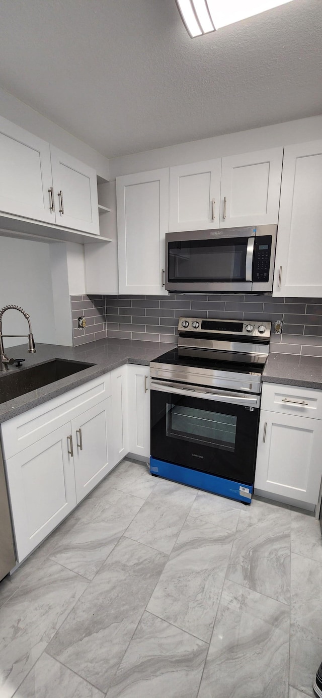 kitchen with decorative backsplash, sink, white cabinets, and stainless steel appliances