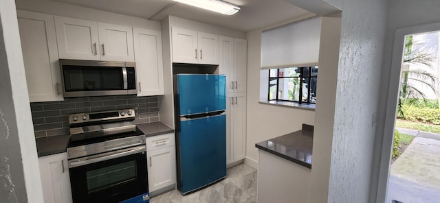 kitchen featuring white cabinets, stainless steel appliances, dark stone counters, and tasteful backsplash