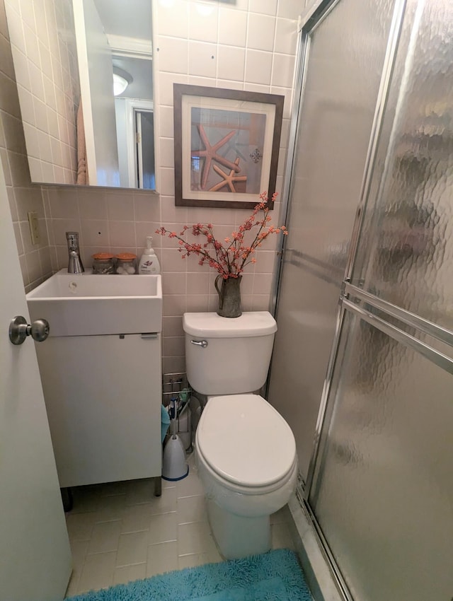 bathroom featuring walk in shower, tile patterned flooring, toilet, vanity, and tile walls