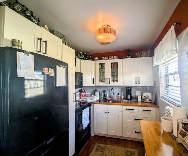 kitchen with black appliances, white cabinets, butcher block counters, and sink