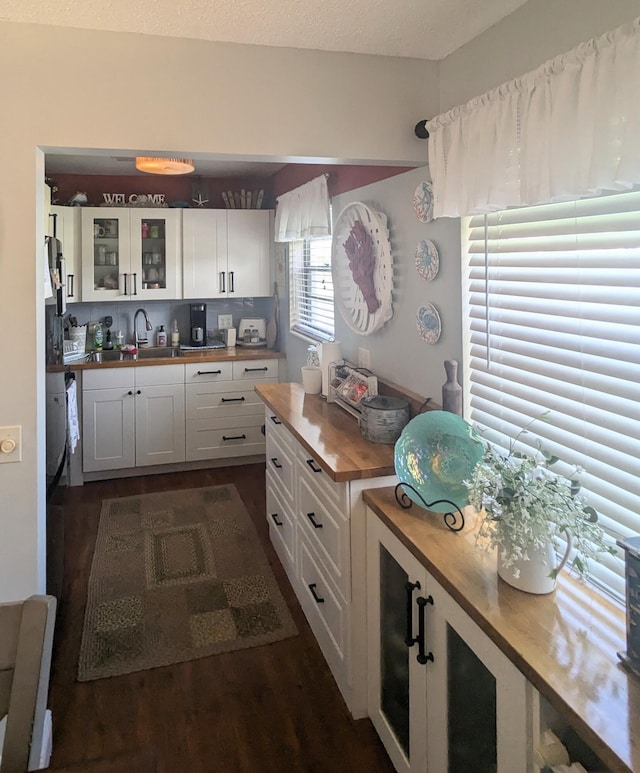 kitchen featuring white cabinets, dark hardwood / wood-style flooring, butcher block counters, and sink