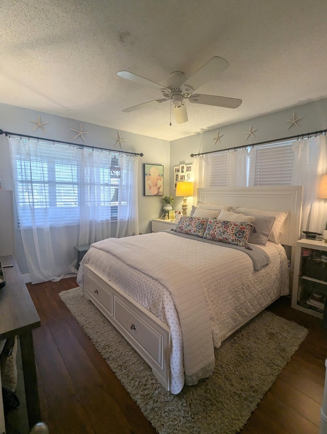 bedroom with a textured ceiling, ceiling fan, and dark hardwood / wood-style floors