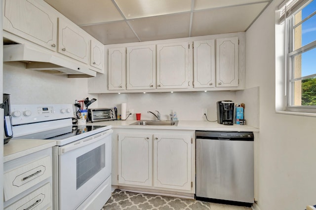 kitchen featuring stainless steel dishwasher, a drop ceiling, sink, electric stove, and white cabinetry