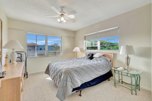 bedroom featuring ceiling fan, light colored carpet, and a textured ceiling