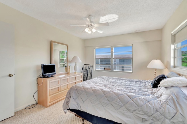 carpeted bedroom featuring ceiling fan and a textured ceiling