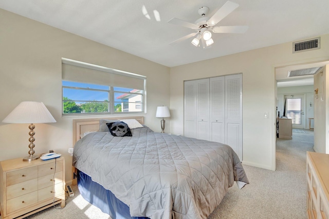 bedroom with ceiling fan, light colored carpet, multiple windows, and a closet