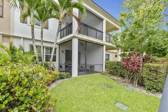 back of house featuring a balcony and a yard