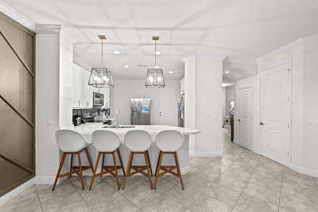 kitchen featuring hanging light fixtures, kitchen peninsula, decorative backsplash, white cabinets, and appliances with stainless steel finishes