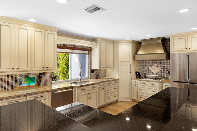 kitchen with cream cabinets, custom exhaust hood, stainless steel appliances, and sink