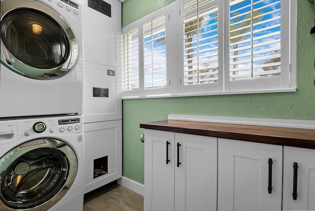 washroom featuring cabinets and stacked washer / dryer