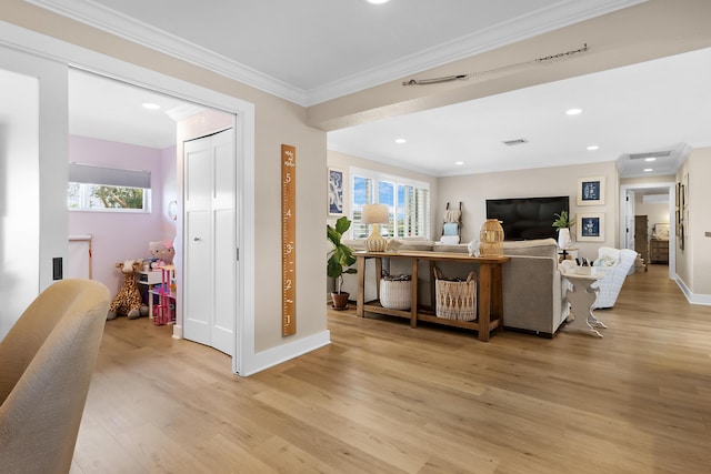 living room with crown molding, a healthy amount of sunlight, and light wood-type flooring