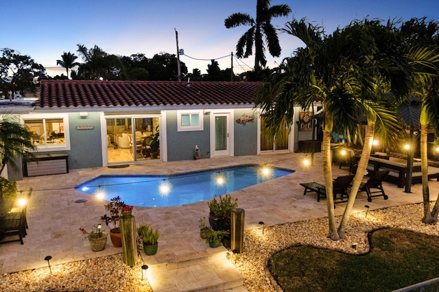 pool at dusk with a patio area