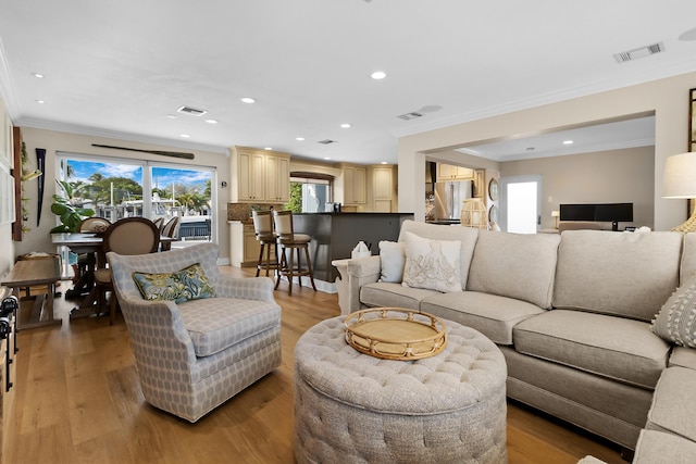 living room with crown molding and light hardwood / wood-style floors