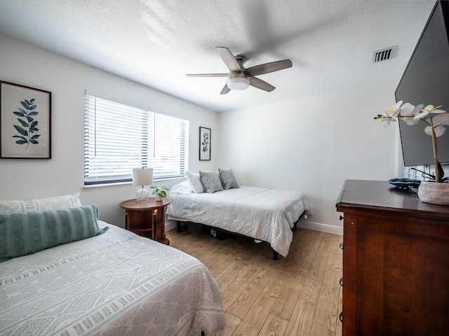 bedroom with ceiling fan, light hardwood / wood-style flooring, and a textured ceiling