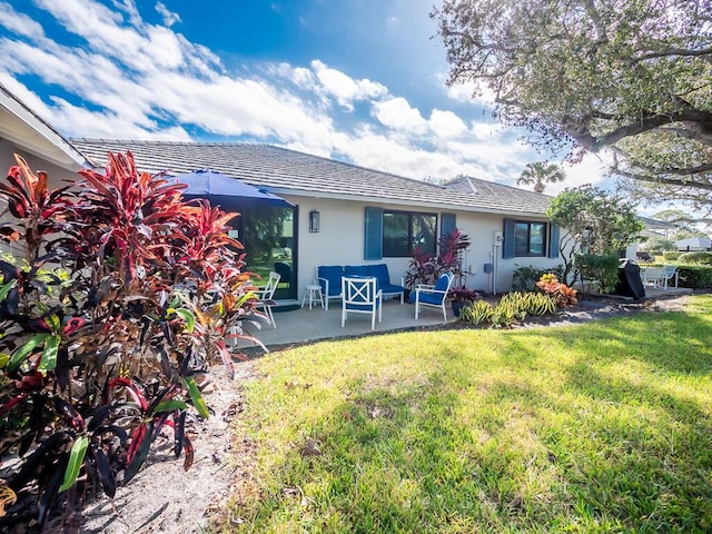 back of property with a lawn and a patio