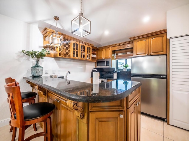 kitchen with a breakfast bar, stainless steel appliances, a center island, hanging light fixtures, and light tile patterned flooring