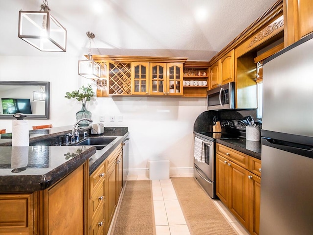 kitchen with dark stone counters, sink, decorative light fixtures, light tile patterned flooring, and stainless steel appliances