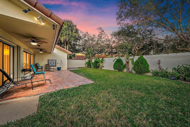 yard at dusk featuring a patio area and ceiling fan