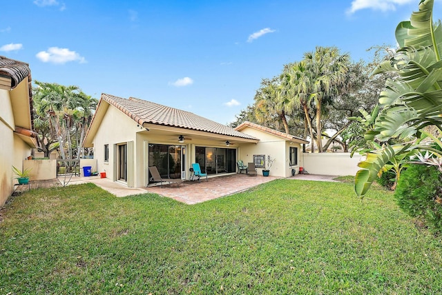 back of property with ceiling fan, a yard, and a patio