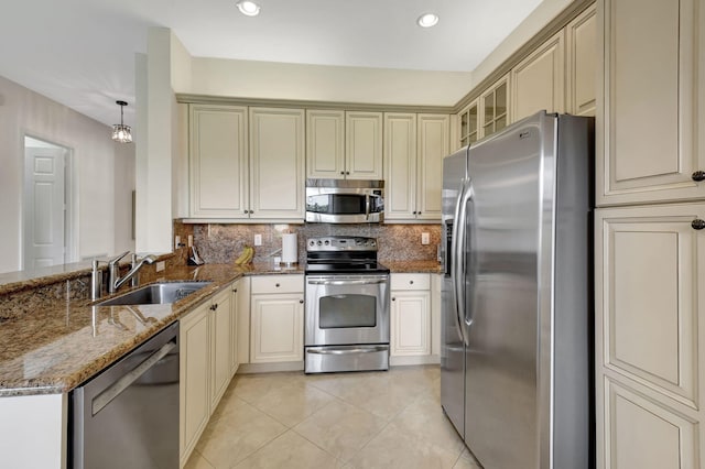 kitchen featuring sink, backsplash, dark stone countertops, decorative light fixtures, and appliances with stainless steel finishes