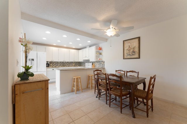 tiled dining room with ceiling fan and a textured ceiling