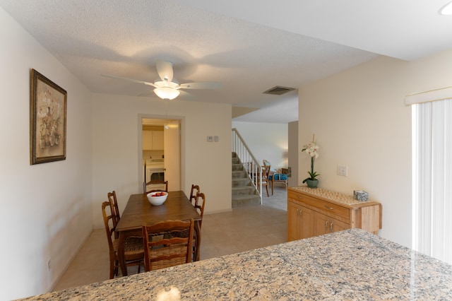 dining room featuring ceiling fan, light tile patterned floors, and a textured ceiling