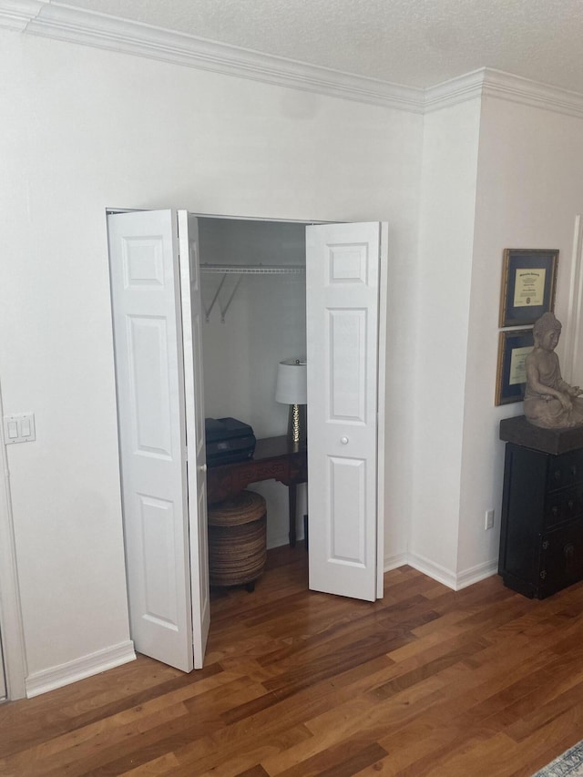 bedroom with crown molding, a closet, dark wood-type flooring, and a textured ceiling