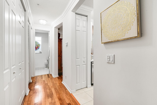 hall with crown molding, a textured ceiling, and light wood-type flooring