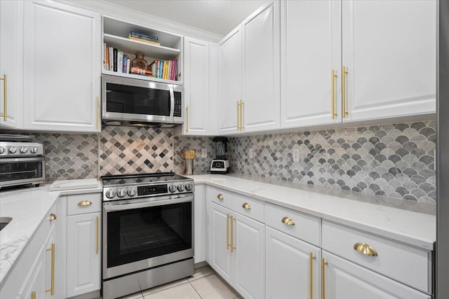 kitchen featuring white cabinets, light tile patterned floors, stainless steel appliances, and light stone counters