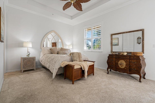 carpeted bedroom with a tray ceiling, ceiling fan, and ornamental molding