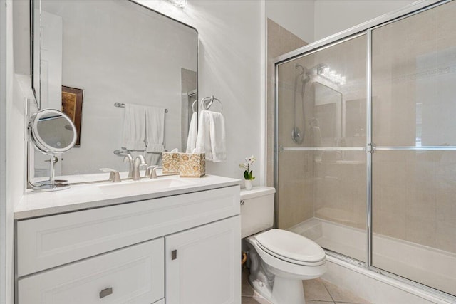 bathroom featuring toilet, vanity, tile patterned floors, and a shower with door