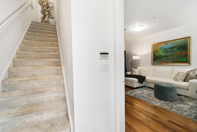 stairs with wood-type flooring, a textured ceiling, and ornamental molding