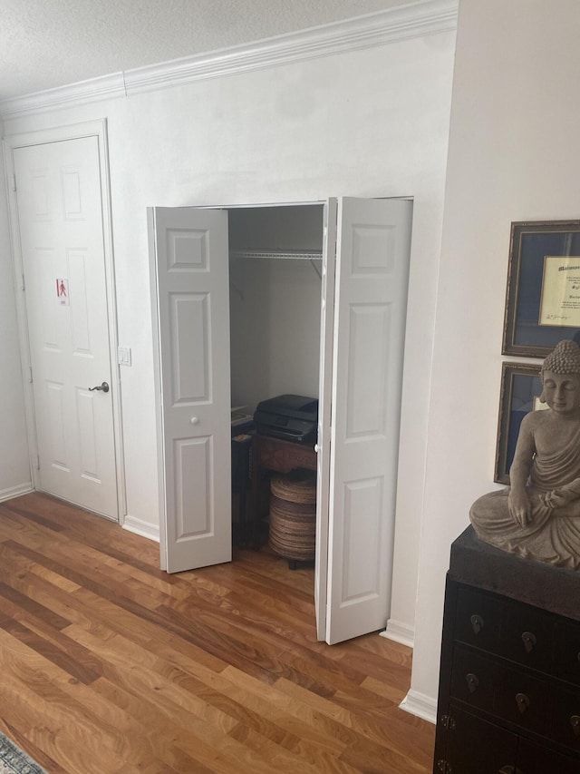 bedroom with hardwood / wood-style floors, crown molding, and a textured ceiling