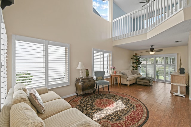 living room featuring hardwood / wood-style floors, ceiling fan, a healthy amount of sunlight, and a towering ceiling