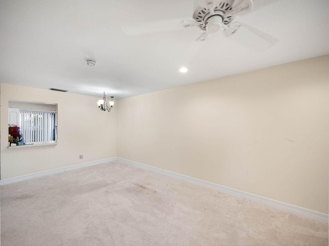 spare room featuring carpet flooring and ceiling fan with notable chandelier