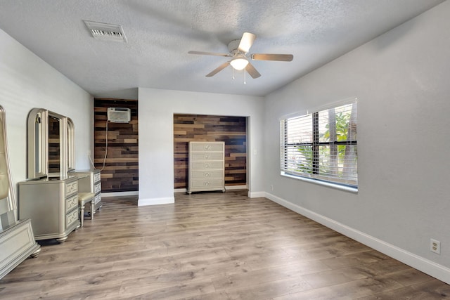 unfurnished living room featuring ceiling fan, light hardwood / wood-style floors, and a textured ceiling