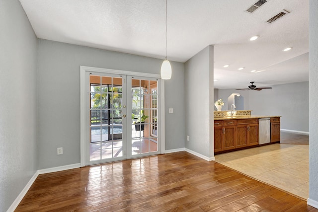 unfurnished dining area featuring ceiling fan, french doors, a textured ceiling, and hardwood / wood-style flooring